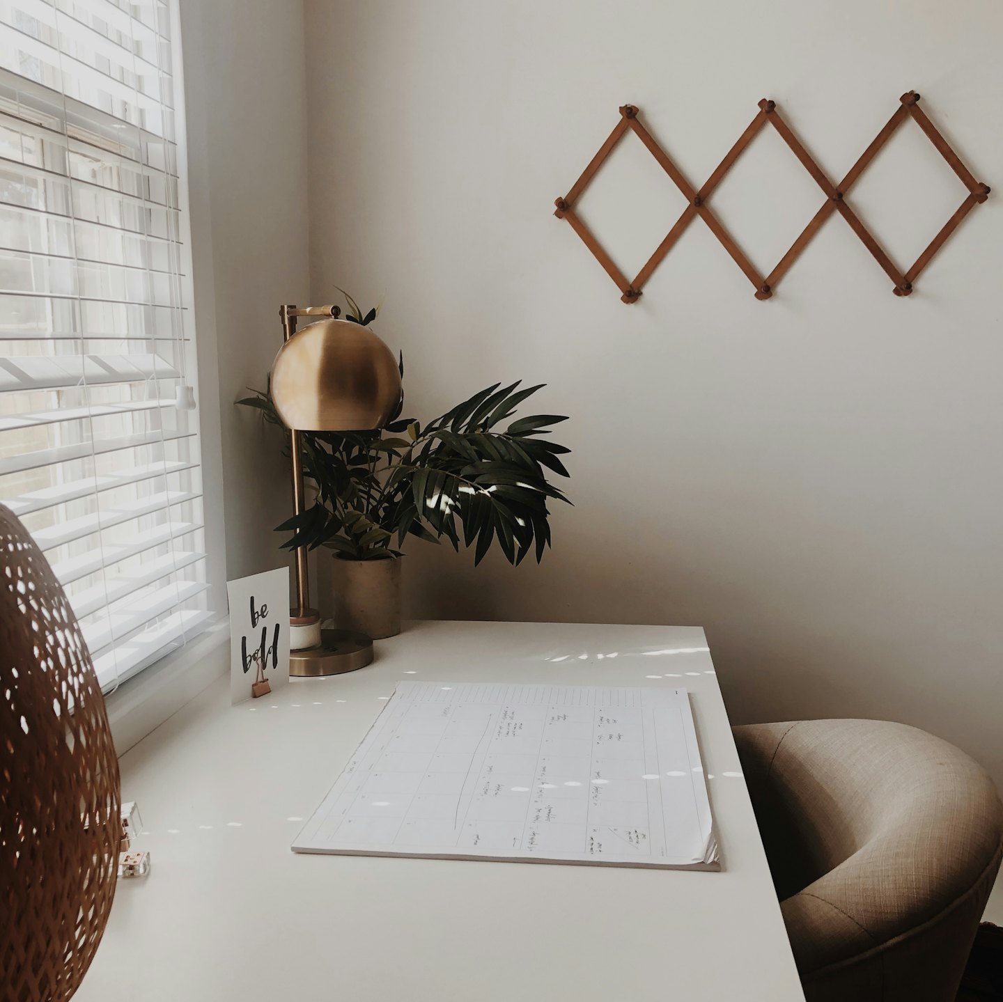 A clean white desk with a brass lamp and green plant.